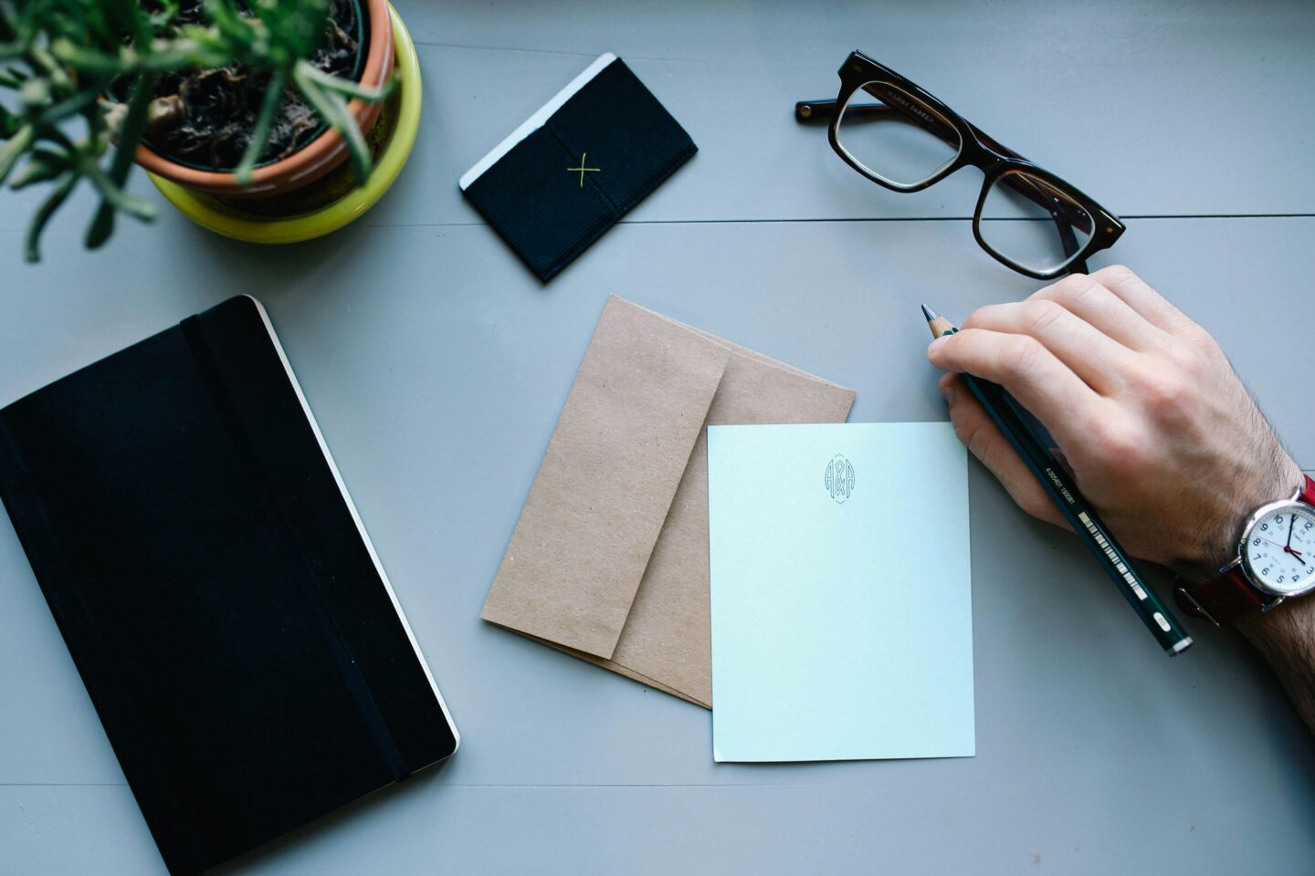 A person's hand writing a letter on a white piece of paper